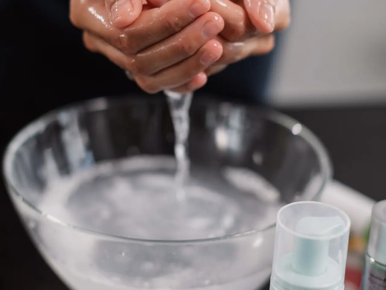 Mãos em procedimento de limpeza de pele com água e produtos de skincare