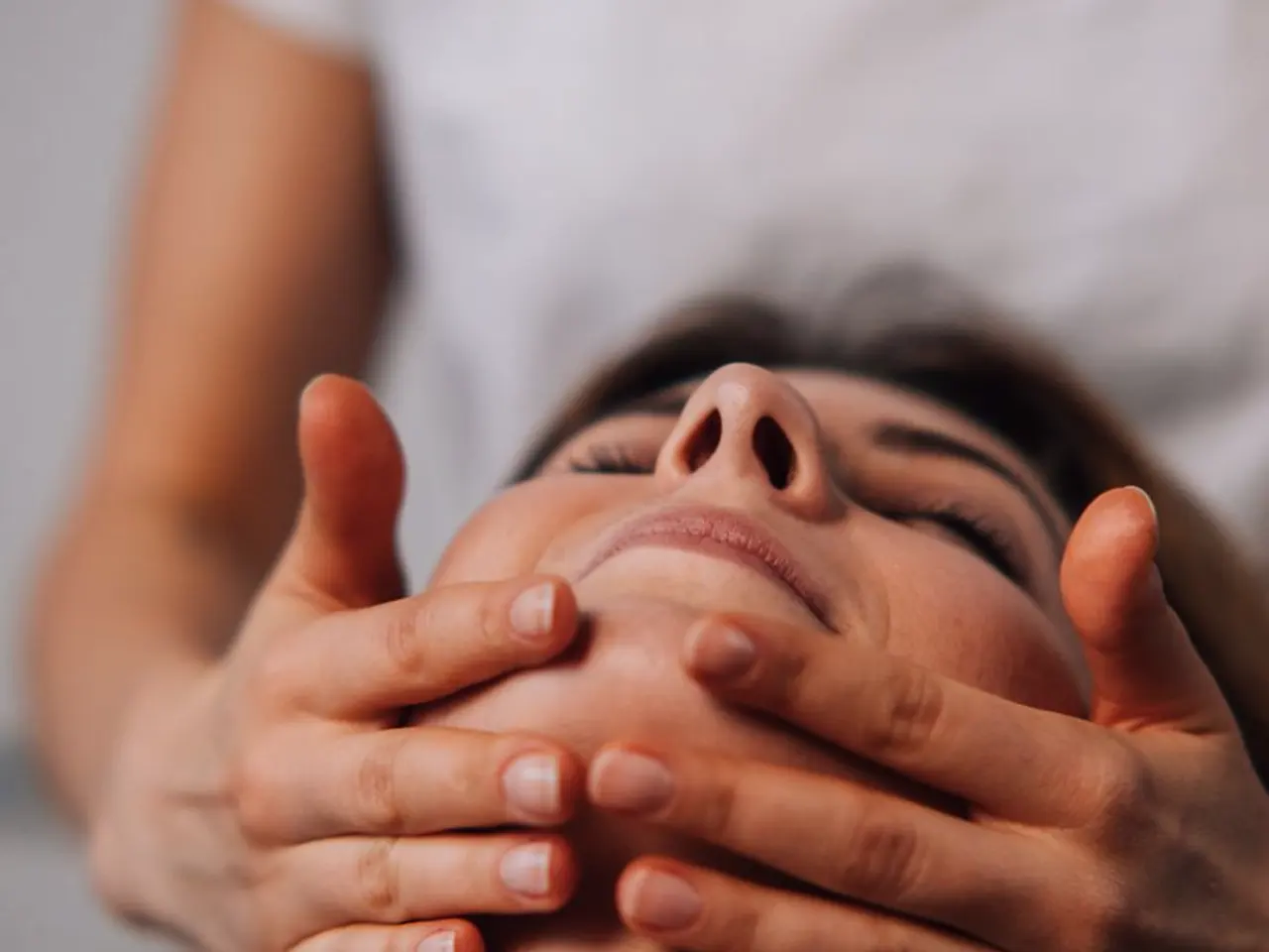Mãos de profissional em procedimento de harmonização facial, toque no contorno do rosto